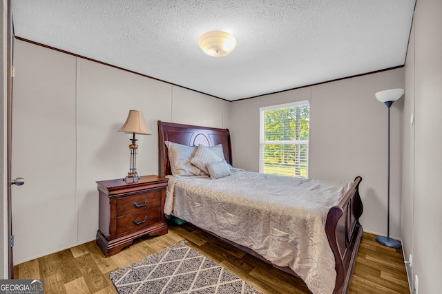 bedroom featuring hardwood / wood-style flooring, a textured ceiling, and ornamental molding