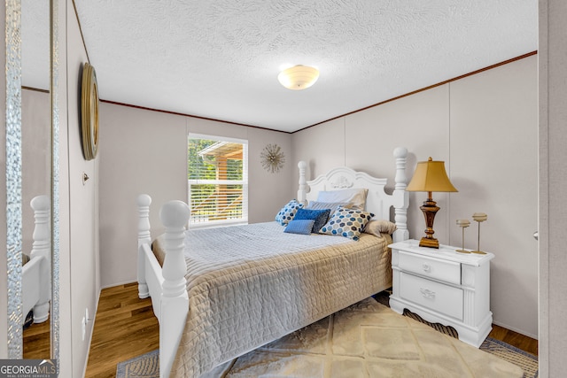 bedroom with ornamental molding, a textured ceiling, and light wood-type flooring