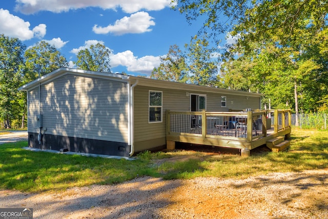 rear view of property featuring a wooden deck and a lawn