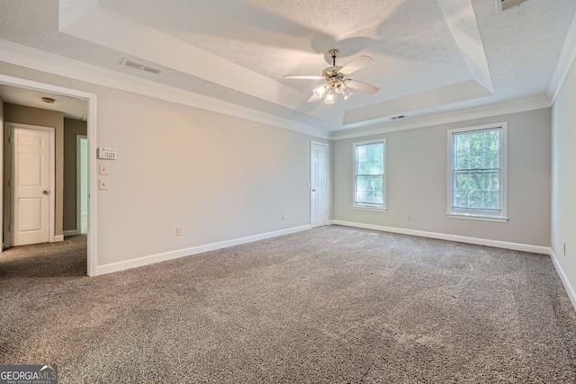 carpeted spare room with a textured ceiling, crown molding, and a tray ceiling