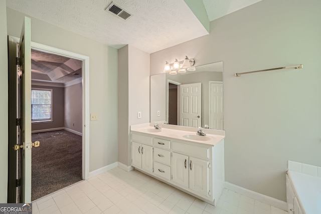 bathroom with vanity, a textured ceiling, beam ceiling, and tile patterned flooring