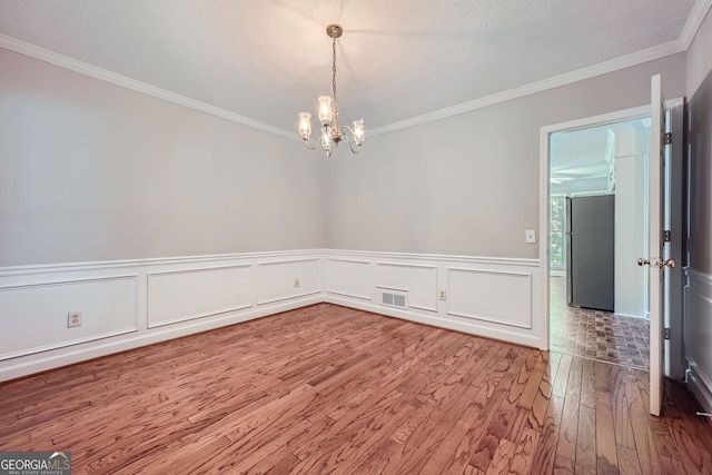 unfurnished room featuring ornamental molding, a textured ceiling, a notable chandelier, and wood-type flooring