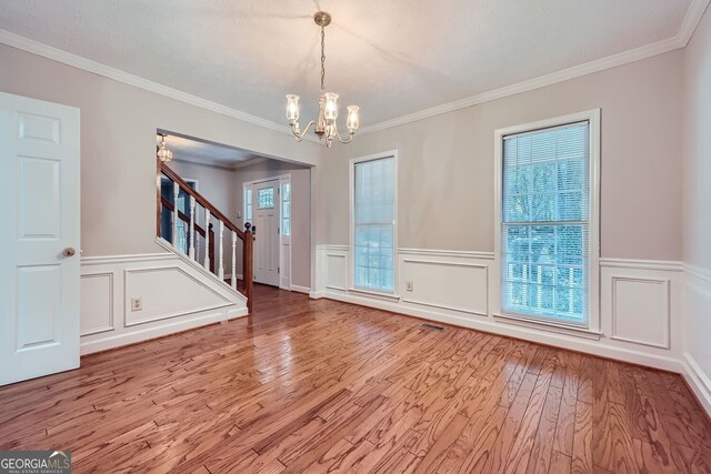 2459 Jacks View Ct, Snellville, GA 30078 - empty room featuring a chandelier, wood finished floors, stairs, wainscoting, and crown molding