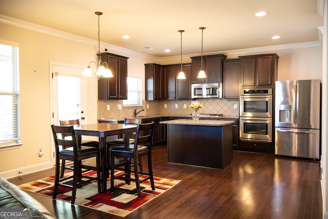 kitchen with dark wood-type flooring, a center island, decorative light fixtures, and stainless steel appliances