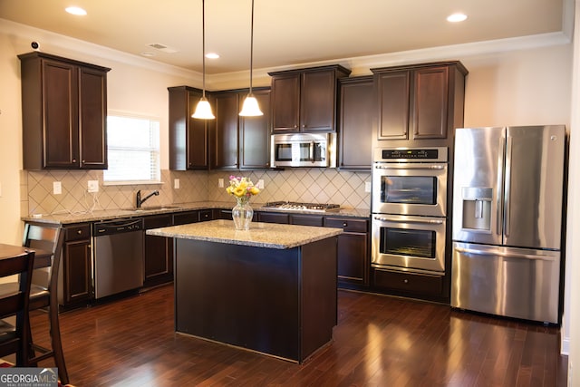 kitchen with stainless steel appliances, a center island, hanging light fixtures, dark hardwood / wood-style floors, and light stone countertops