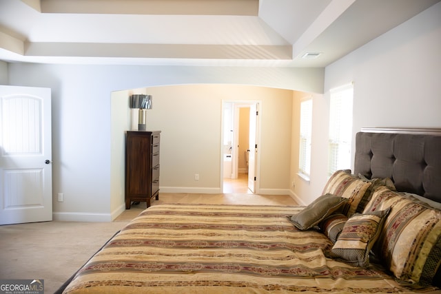 bedroom with light carpet and a tray ceiling