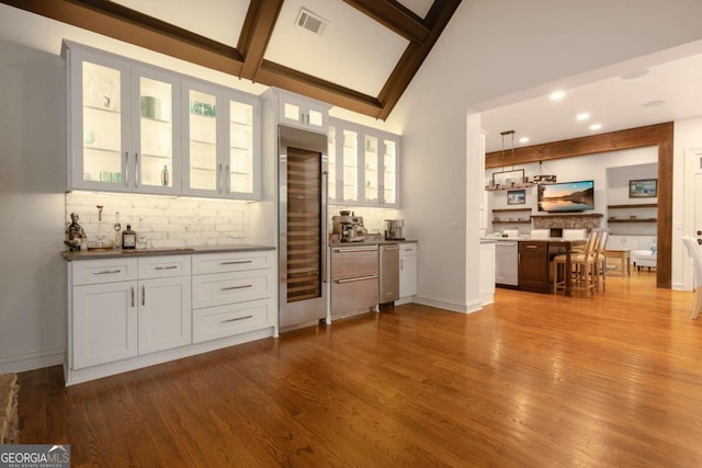 bar featuring white cabinets, tasteful backsplash, stainless steel dishwasher, light hardwood / wood-style flooring, and decorative light fixtures