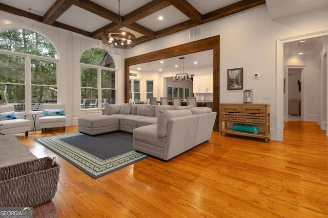 living room with a wealth of natural light, a chandelier, and light hardwood / wood-style floors