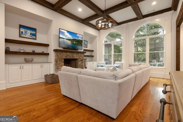 living room with light hardwood / wood-style floors, a notable chandelier, coffered ceiling, and a wealth of natural light