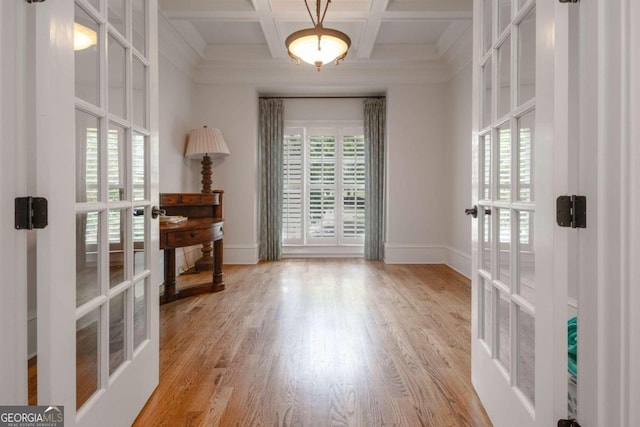 empty room with beam ceiling, french doors, light hardwood / wood-style flooring, and coffered ceiling