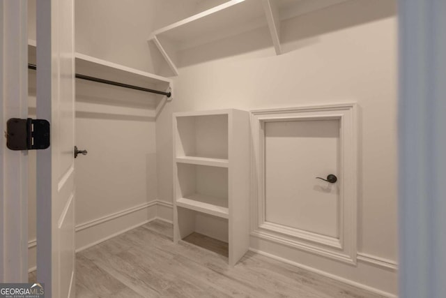 walk in closet with light hardwood / wood-style flooring