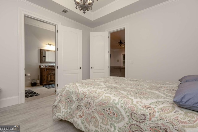 bedroom featuring ensuite bath, ornamental molding, light hardwood / wood-style flooring, and a chandelier