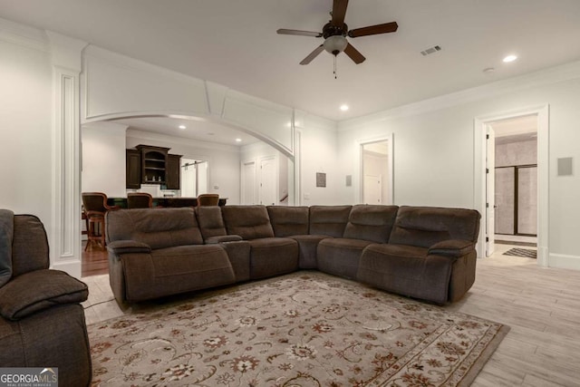 living room featuring ornamental molding, light hardwood / wood-style floors, and ceiling fan