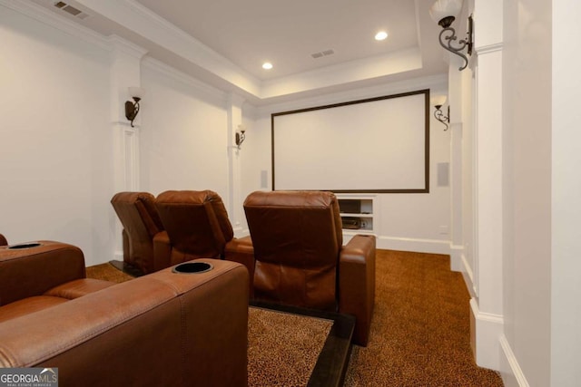 carpeted home theater room with crown molding and a tray ceiling