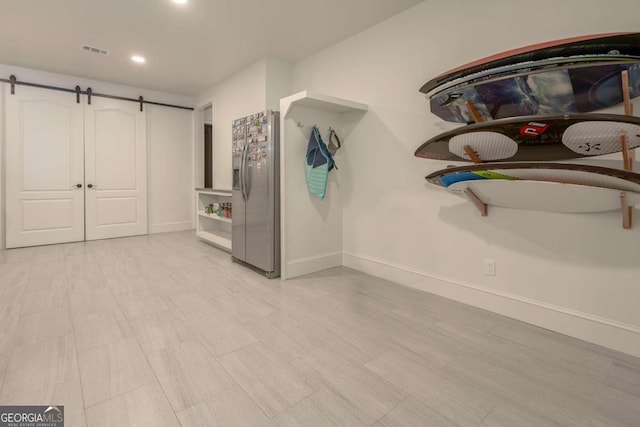 interior space with stainless steel fridge and a barn door