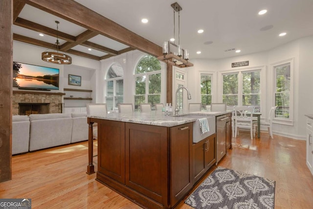 kitchen with hanging light fixtures, light wood-type flooring, and an island with sink