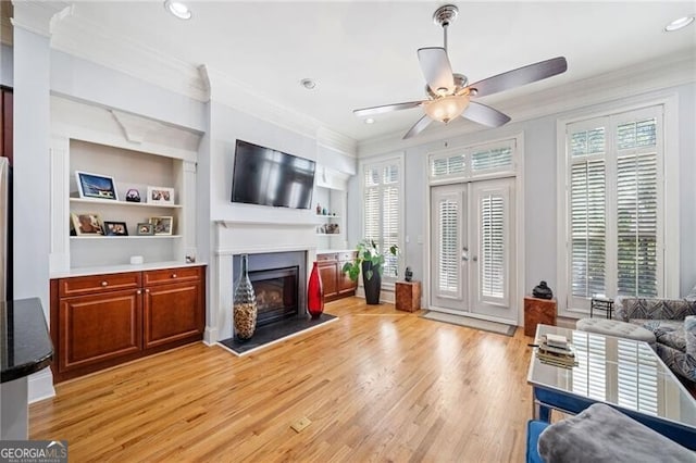 living room with light wood-type flooring, ornamental molding, and plenty of natural light