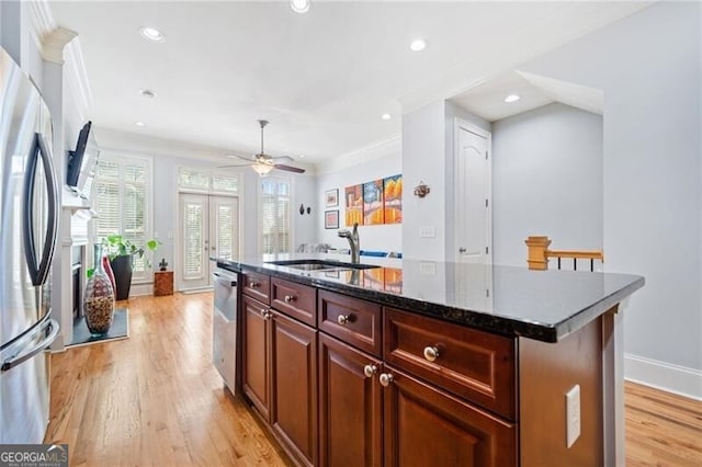 kitchen with a kitchen island with sink, sink, appliances with stainless steel finishes, light hardwood / wood-style floors, and ceiling fan