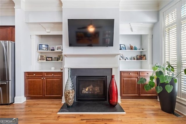 living room featuring light hardwood / wood-style flooring, built in shelves, and crown molding