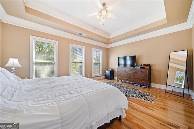 bedroom featuring ceiling fan, a raised ceiling, crown molding, and hardwood / wood-style floors