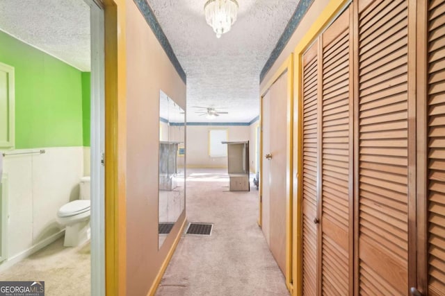 hallway with a textured ceiling and light colored carpet