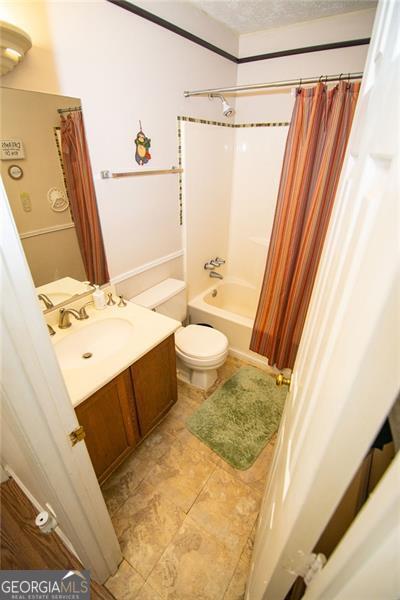 full bathroom featuring vanity, toilet, shower / bathtub combination with curtain, and a textured ceiling