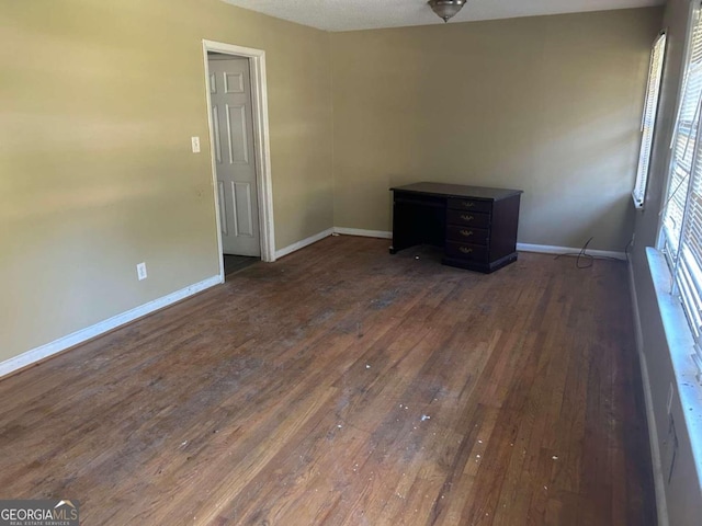 empty room with a textured ceiling and dark hardwood / wood-style flooring