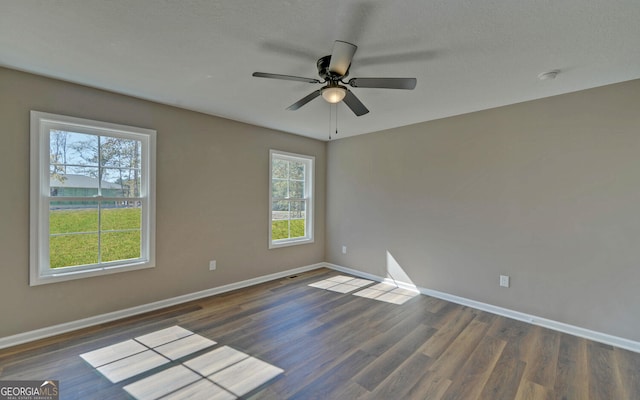 unfurnished room with dark hardwood / wood-style floors, a healthy amount of sunlight, a textured ceiling, and ceiling fan