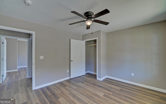 unfurnished bedroom featuring a closet, dark hardwood / wood-style floors, a textured ceiling, and ceiling fan