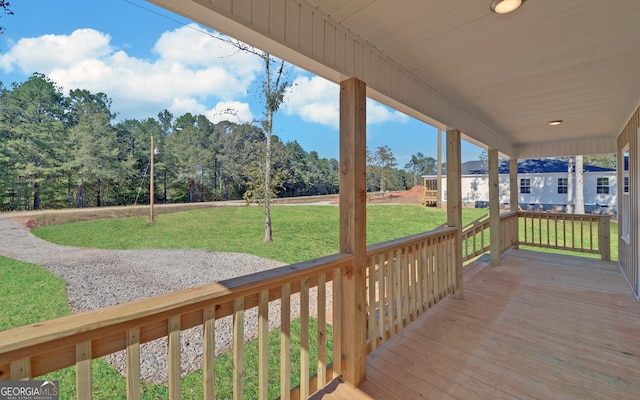 wooden terrace featuring covered porch and a lawn