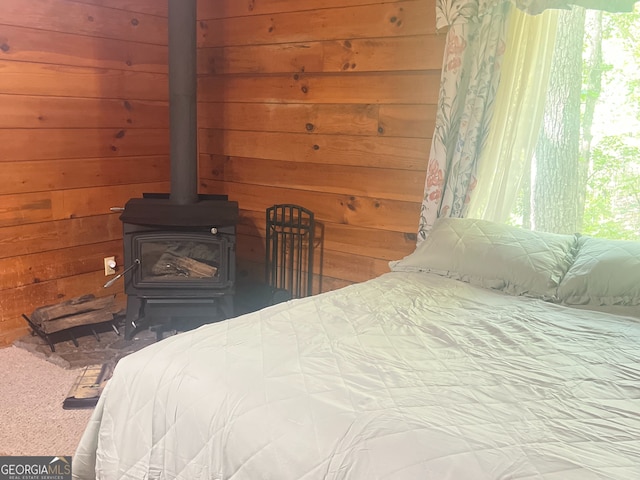 bedroom with a wood stove, wooden walls, and multiple windows