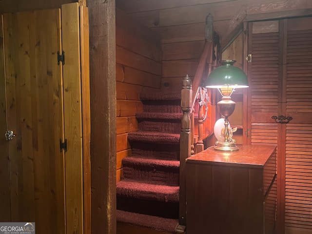 staircase featuring wooden walls