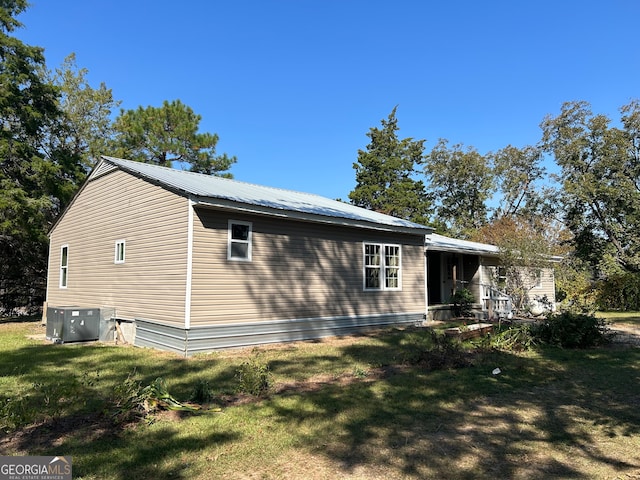 view of side of property with central AC and a lawn