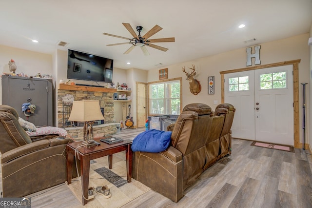 living room featuring light hardwood / wood-style flooring, a healthy amount of sunlight, a fireplace, and ceiling fan