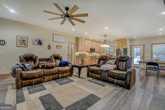 living room featuring light hardwood / wood-style flooring and ceiling fan with notable chandelier