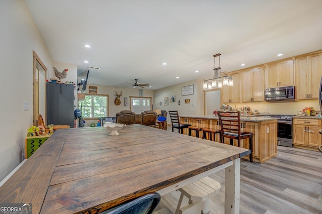 dining area with light hardwood / wood-style flooring and ceiling fan