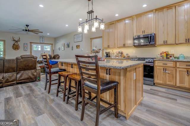 kitchen with a breakfast bar area, a kitchen island, light wood-type flooring, and electric range oven