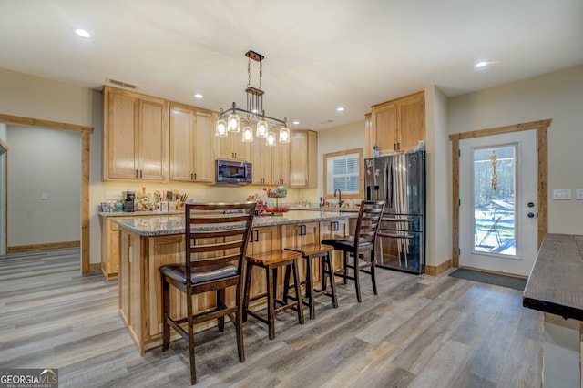 kitchen with appliances with stainless steel finishes, a center island, and light wood-type flooring