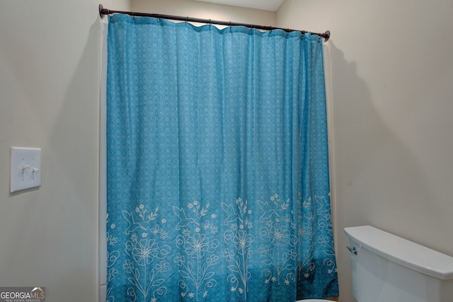 bathroom featuring a shower with curtain and toilet