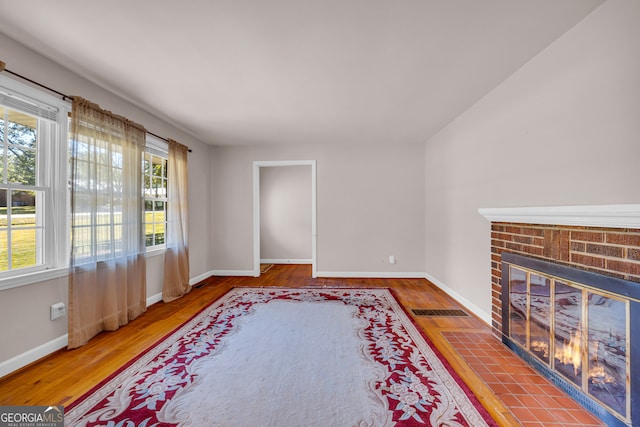 living room with a brick fireplace and hardwood / wood-style flooring