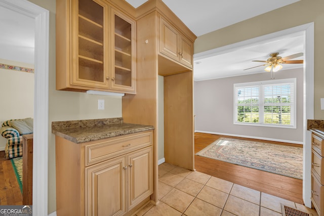 kitchen with dark stone counters, light wood-type flooring, and ceiling fan