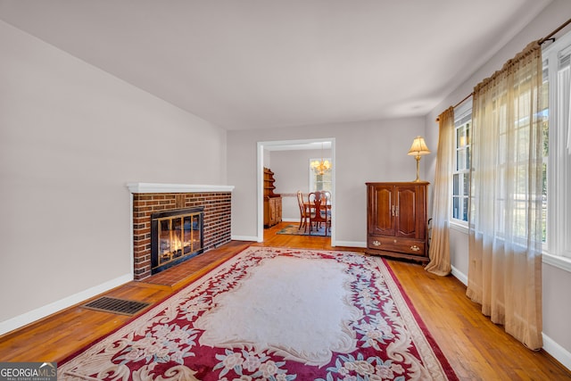 living room featuring a brick fireplace and light wood-type flooring