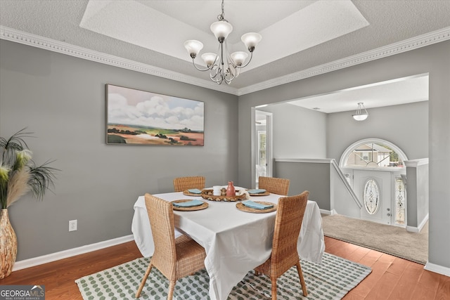 dining space with a notable chandelier, ornamental molding, hardwood / wood-style flooring, and a textured ceiling