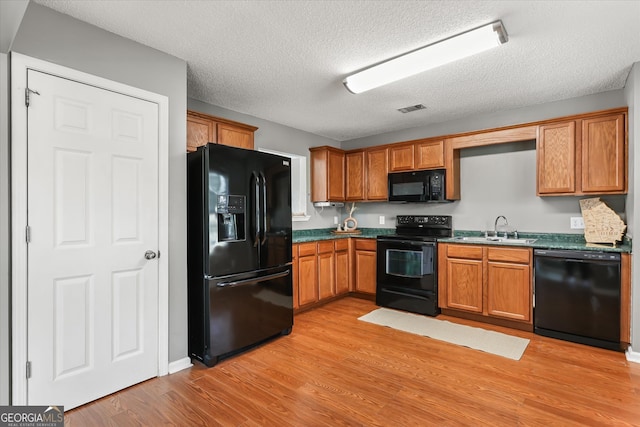 kitchen with light hardwood / wood-style flooring, a textured ceiling, black appliances, and sink