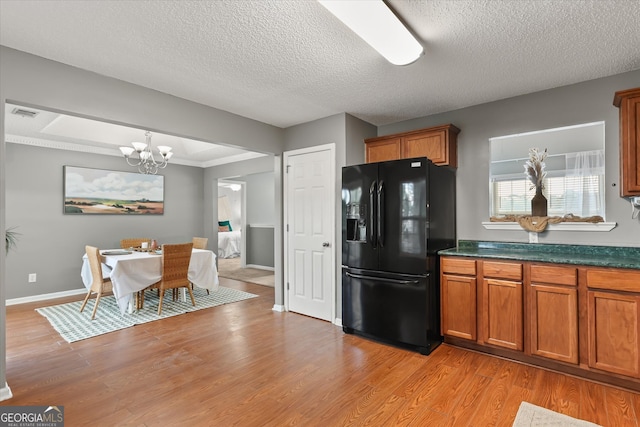 kitchen with light hardwood / wood-style floors, a textured ceiling, pendant lighting, and black fridge