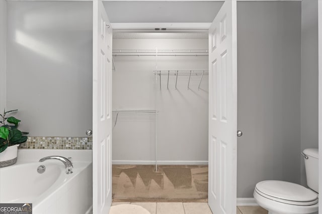 bathroom featuring tiled tub, toilet, and tile patterned flooring