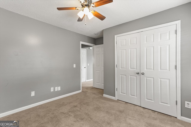 unfurnished bedroom with light carpet, a textured ceiling, a closet, and ceiling fan