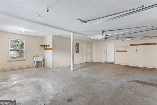 garage with a garage door opener, electric panel, and sink