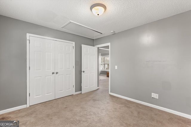 unfurnished bedroom with light carpet, a closet, and a textured ceiling