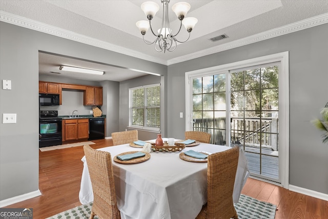 dining area featuring crown molding, wood-type flooring, and a textured ceiling